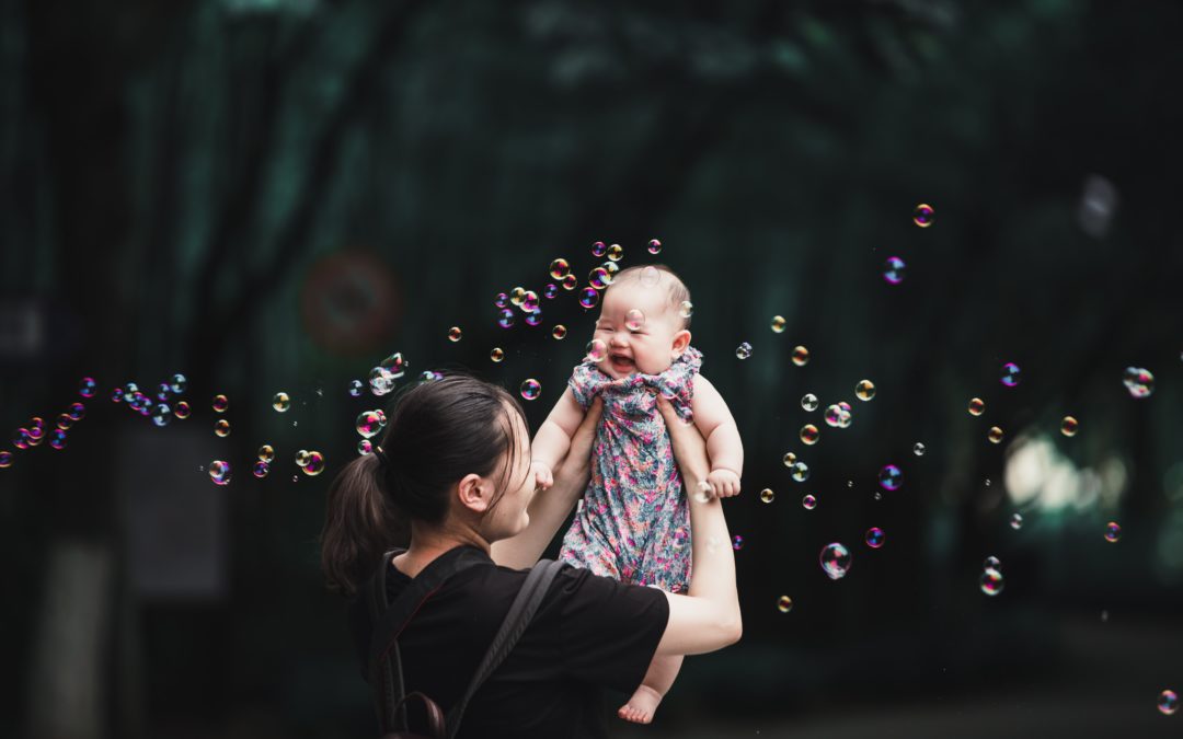 girl in black and pink dress blowing bubbles