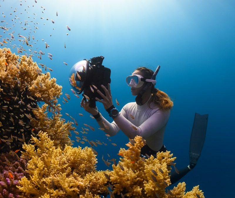 a woman is taking a picture of a coral reef
